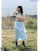 A woman standing in a field talking on a cell phone.