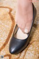 A woman's feet in black shoes on a carpeted floor.