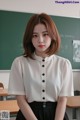 a woman sitting at a desk in front of a blackboard