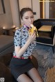 A woman sitting on a table eating a banana.