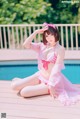 A woman in a pink bikini sitting by a pool.