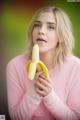 A woman holding a banana in front of her mouth.