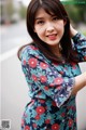 A woman in a blue and red floral dress posing for a picture.