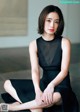 A woman in a black dress sitting on the floor.